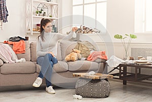 Desperate woman sitting on sofa in messy room