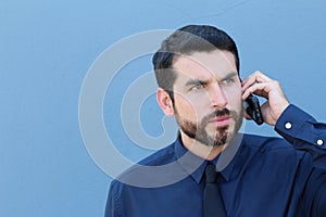 Desperate young brunette businessman get bad news heavy problems, faces challenges snort while talking on the mobile phone on blue photo