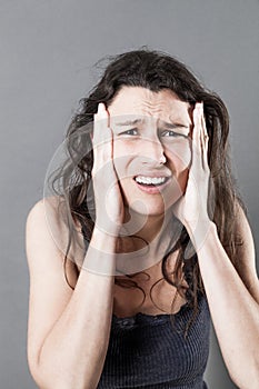 Desperate young woman holding her face for stressful migraine