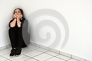 Desperately disappointed teenager squats in a corner