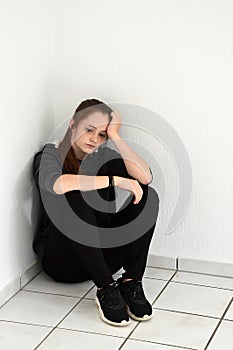 Desperately disappointed teenager squats in a corner