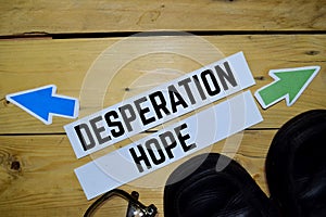 Desperation or Hope opposite direction signs with eyeglasses and boots on wooden