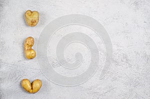 Despicable potatoes of different shapes on a gray background, copy space