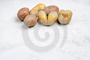 Despicable potatoes of different shapes on a gray background, copy space