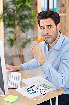 despondent businessman eats bland carrot photo