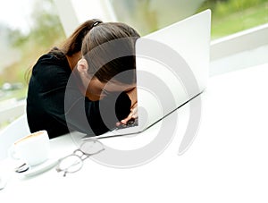 Despondent businesswoman leaning over her laptop photo