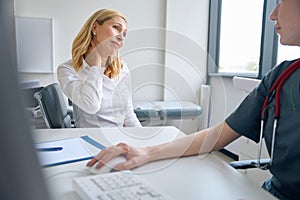 Despondent lady complaining of cervicalgia to neurologist in office photo