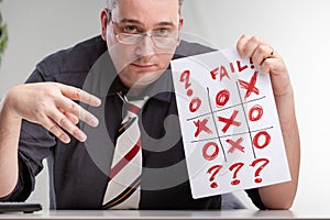 Despondent man holding up a tic-tac-toe game