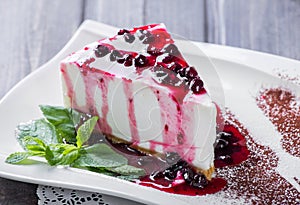 Dessert Cheesecake with Berries Sauce and green mint in plate on dark background