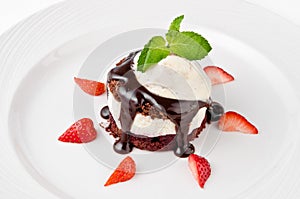 Dessert with chocolate sponge cake, vanilla cream, cherry, ice cream and strawberries