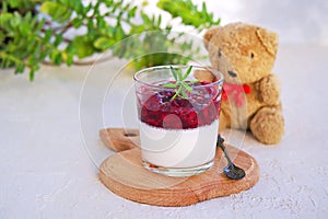 Dessert, creamy panna cotta with cherry sauce in glass glasses on a light concrete background