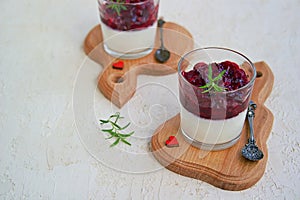 Dessert, creamy panna cotta with cherry sauce in glass glasses on a light concrete background