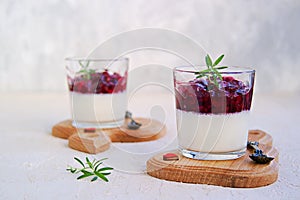 Dessert, creamy panna cotta with cherry sauce in glass glasses on a light concrete background. Desserts without baking. Desserts