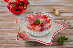 Dessert, creamy panna cotta with fresh strawberries in a glass flat bowl on a light wooden background. Dessert recipes without