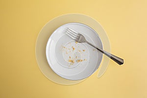 Dessert crumbs in round plate with fork on yellow background photo