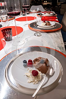 Dessert on festive table. Silver plates on red placemats on marble top