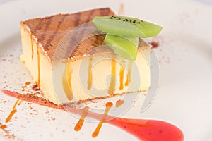 Dessert of mellow cheese cake with caramel and two slices of kiwi.