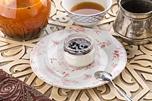 Dessert panna cotta with cherry jam and cup of black tea on oriental wooden table