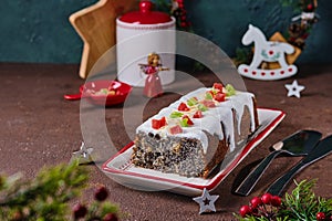 Dessert, Polish poppy seed cake with apples and candied fruits, covered with sugar icing, in Christmas style on a brown concrete