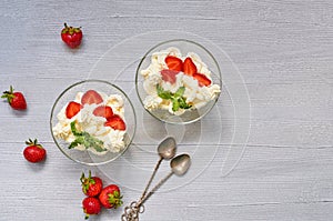 Dessert with sliced strawberries and cream cheese in the glass bowls on a gray background with copy space