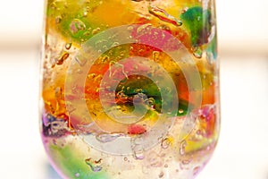 Rainbow Jelly in a cup of glass pink light background photo