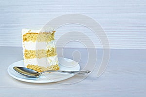 Dessertspoon and a slice of vanilla bisquits with butter cream. White background