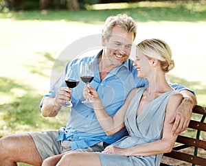 Destressing together. Happy mature couple toasting their love with two glasses of wine while outdoors.