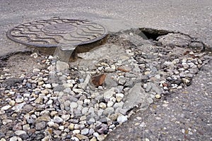 Destroyed asphalt road, hole next to sanitary sewer manhole