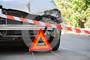 Destroyed car in car crash traffic accident on city road. Smashed broken car in accident. Red emergency stop triangle