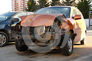 Destroyed car in traffic accident on city road. Smashed broken front of auto after crash.