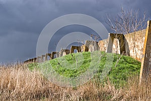 Destroyed concrete structure of an old abandoned farm on a background of dark blue clouds.