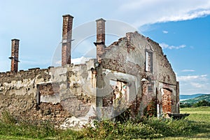 Destroyed old brick house without roof and with chimneys, broken windows, window frames, door and bricks