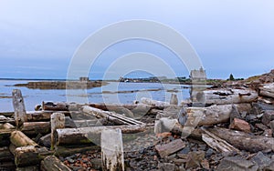 Destroyed pier and an old log cabin on the shore, on a small des