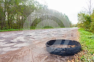 Destroyed rubber car tire car on rural bumpy broken road.