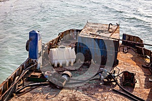 Destroyed and rusty deck of a cargo ship washed ashore, with old ropes, pipes, machinery and equipment