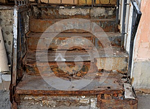 Destroyed rusty metal staircase to door of old brick house