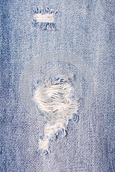 Destroyed Torn Blue jeans background. Close up blue ripped jeans