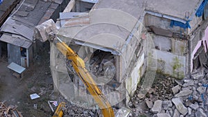 Destroying Old Concrete House Using Mechanical Arm of Bulldozer on Construction Site