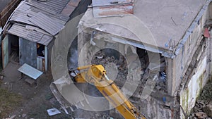 Destroying old house using bucket excavator on construction site.