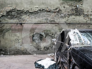 Destructed car near ramshackle wall