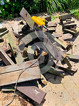 Destruction of old beat-up wood picnic tabler by use of power saw.