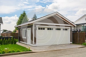 Detached garage of residential house with asphalt road in front.