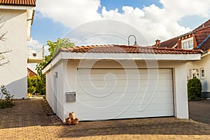 Detached white garage with orange brick tile roof