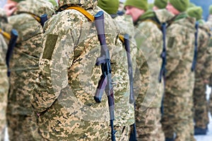 A detachment of soldiers with Kalashnikov assault rifles stand in formation to prepare for battle and offensive