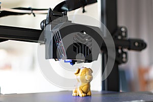 Detail of a 3D printer printing a model with a gold biodegradable PLA filament, ecofil, blue light