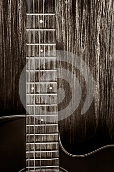 Detail of acoustic guitar in vintage style on wood background