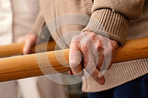 Detail of aged human hands grabbing parallel rehabilitation bars