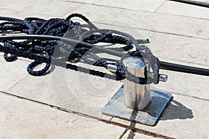 Detail of an anchor rope on a yacht, Stainless steel boat mooring cleat with knotted rope mounted on white yacht deck