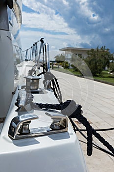 Detail of an anchor rope on a yacht, Stainless steel boat mooring cleat with knotted rope mounted on white yacht deck