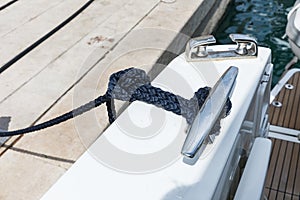 Detail of an anchor rope on a yacht, Stainless steel boat mooring cleat with knotted rope mounted on white yacht deck